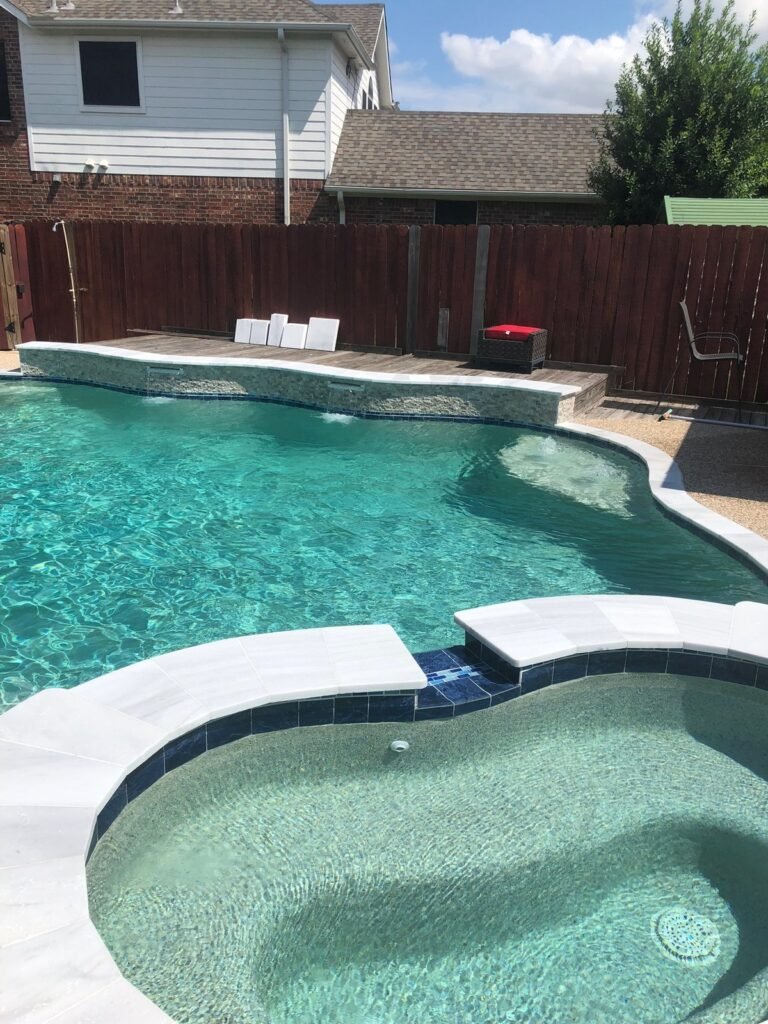 Raised wall with sheer spillovers into a modern pool and spa