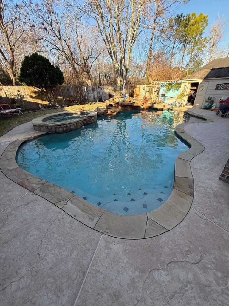 Freeform pool with a rock waterfall, spa and flagstone deck