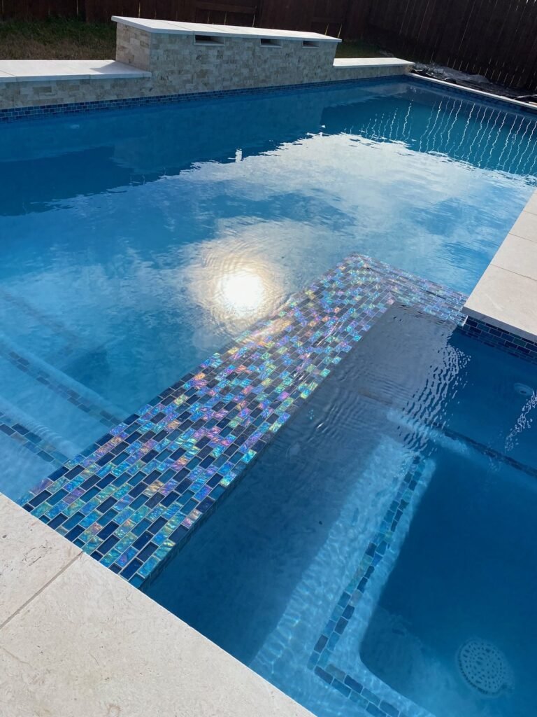 Iridescent glass tile spillway ledge between spa and pool